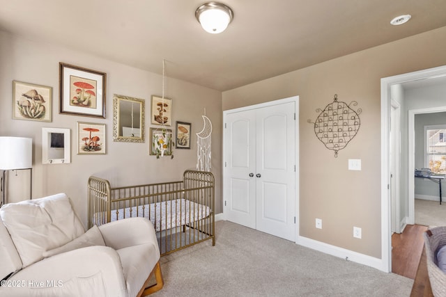 carpeted bedroom featuring a closet and a crib