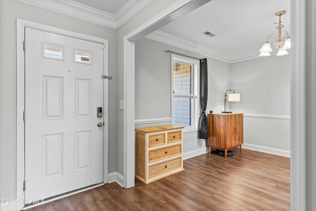 foyer featuring a notable chandelier, ornamental molding, and dark wood-type flooring