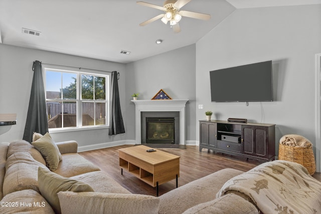 living room with ceiling fan, light hardwood / wood-style flooring, and vaulted ceiling