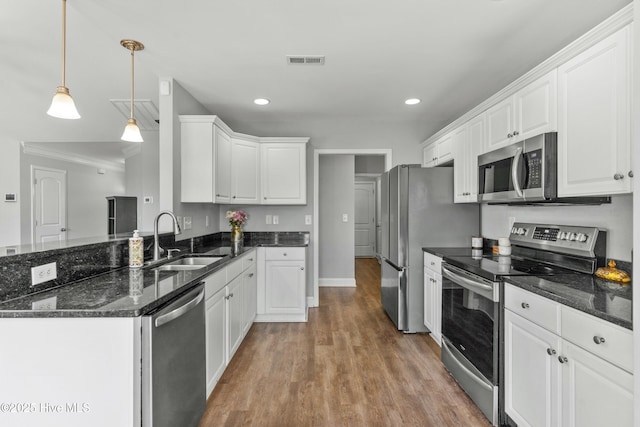 kitchen with decorative light fixtures, sink, white cabinetry, and stainless steel appliances