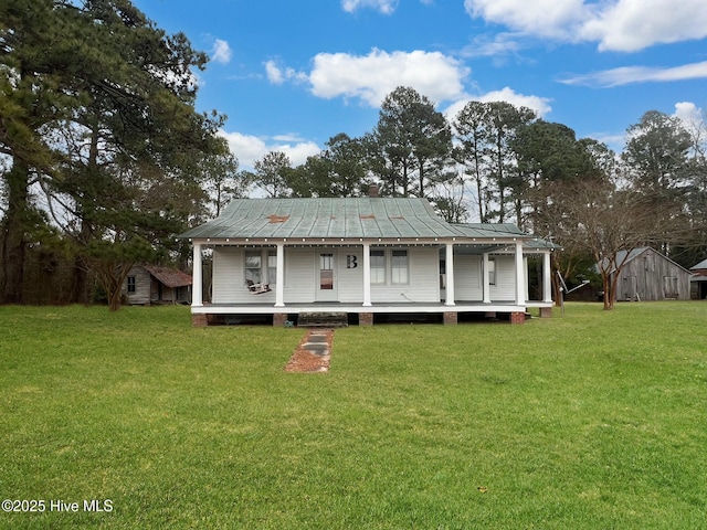 back of property with covered porch, a yard, and a storage unit