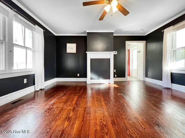 unfurnished living room featuring wood-type flooring, a wealth of natural light, and ornamental molding