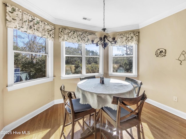 dining space with wood-type flooring, ornamental molding, and plenty of natural light