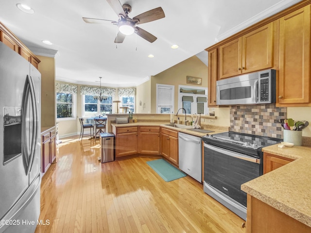 kitchen with pendant lighting, sink, light hardwood / wood-style flooring, appliances with stainless steel finishes, and backsplash