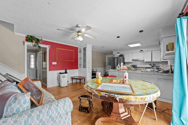 dining area with ceiling fan, crown molding, a textured ceiling, and light wood-type flooring