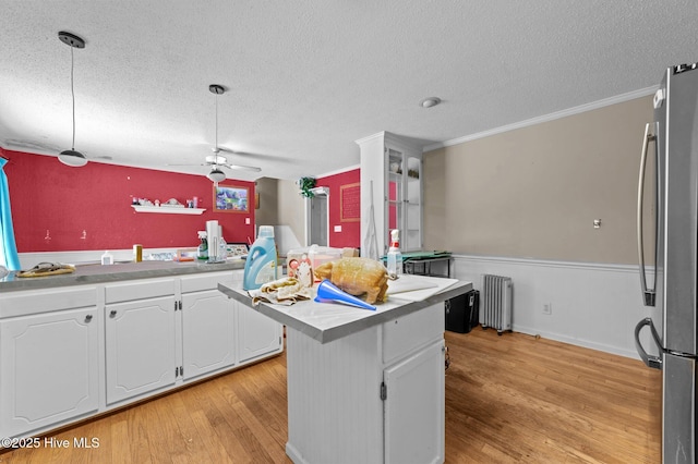 kitchen featuring decorative light fixtures, stainless steel refrigerator, ornamental molding, radiator, and white cabinets