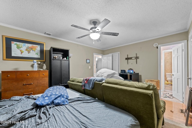 bedroom featuring a textured ceiling, ensuite bath, ornamental molding, and ceiling fan