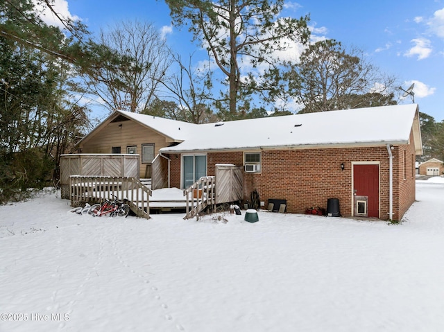 snow covered rear of property with a deck