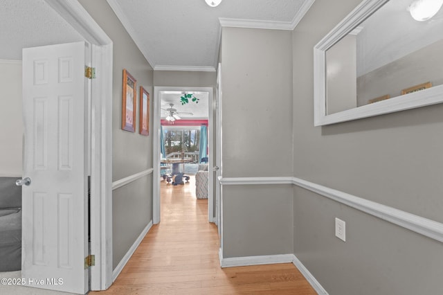 hallway with crown molding, a textured ceiling, and light wood-type flooring