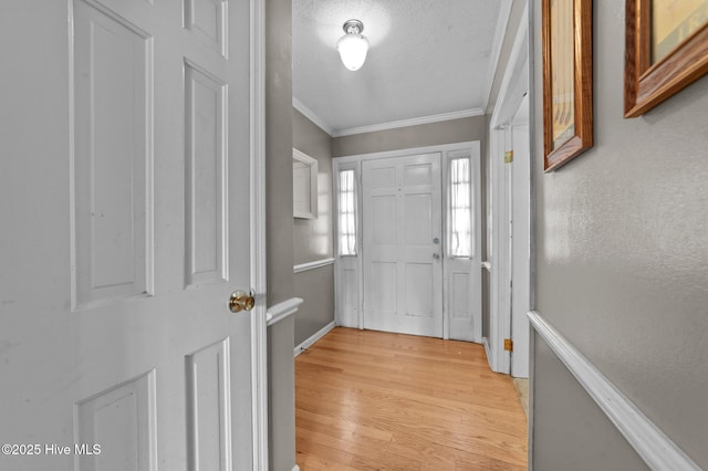 entrance foyer featuring crown molding, light hardwood / wood-style flooring, and a textured ceiling