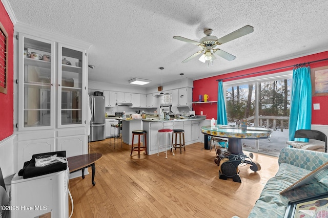 living room featuring ceiling fan, a textured ceiling, and light hardwood / wood-style flooring