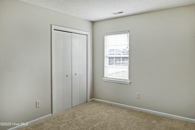 unfurnished bedroom featuring a textured ceiling, a closet, and carpet flooring