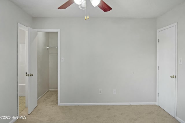 unfurnished bedroom with ceiling fan, light colored carpet, a closet, and a spacious closet