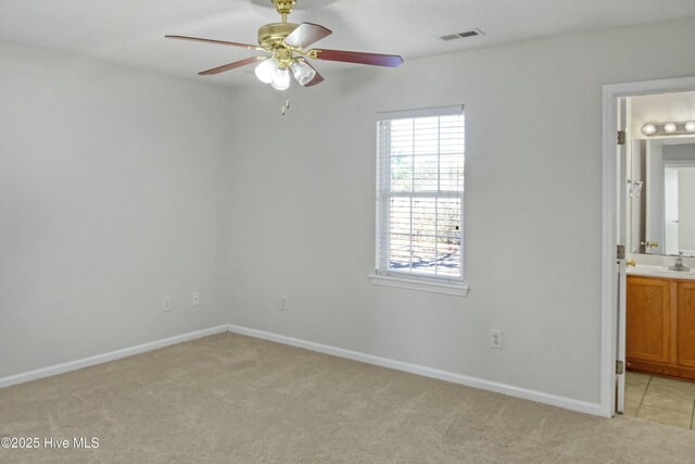 unfurnished bedroom with ceiling fan, sink, ensuite bathroom, and light carpet