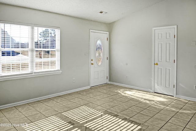 entryway with a textured ceiling and light tile patterned flooring