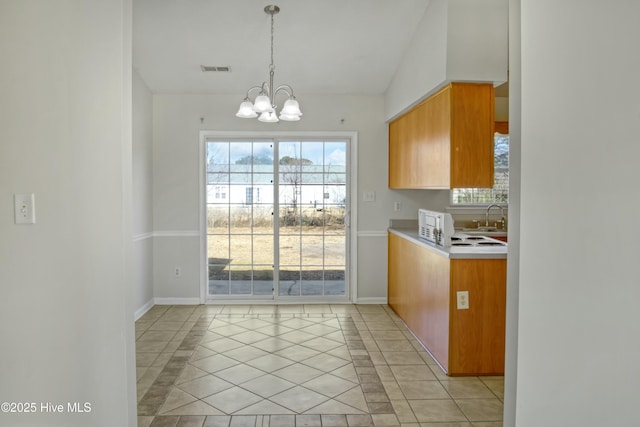 kitchen with decorative light fixtures, lofted ceiling, sink, light tile patterned flooring, and an inviting chandelier