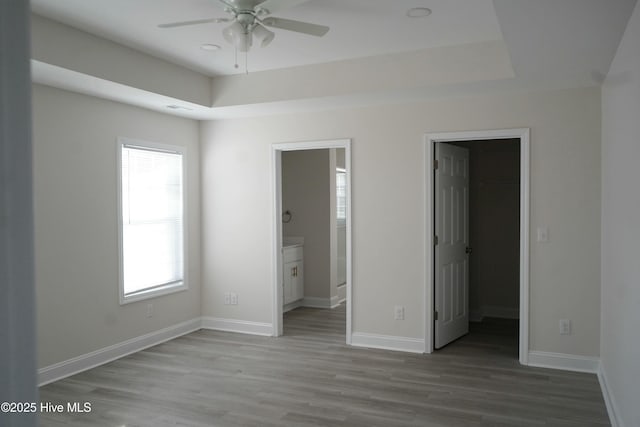 unfurnished bedroom with multiple windows, ensuite bathroom, a closet, and a walk in closet