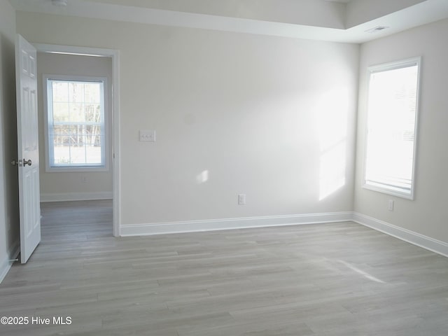 spare room featuring a healthy amount of sunlight and light hardwood / wood-style floors