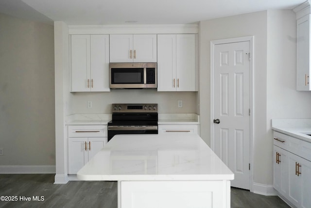 kitchen featuring a kitchen island, white cabinetry, light stone countertops, and stainless steel appliances