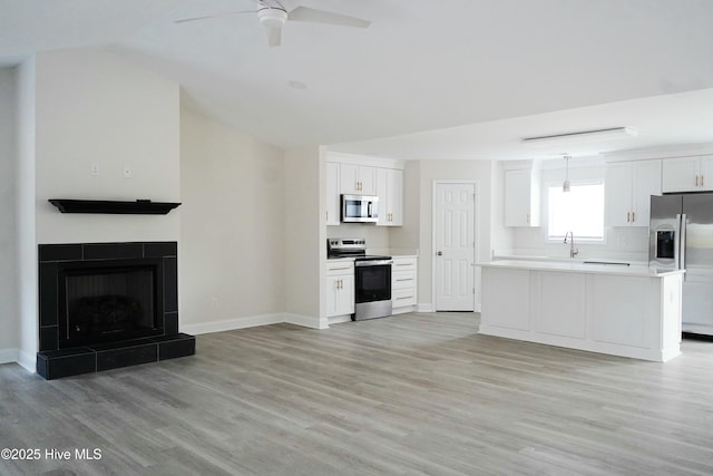 kitchen with white cabinets, decorative light fixtures, appliances with stainless steel finishes, and light wood-type flooring