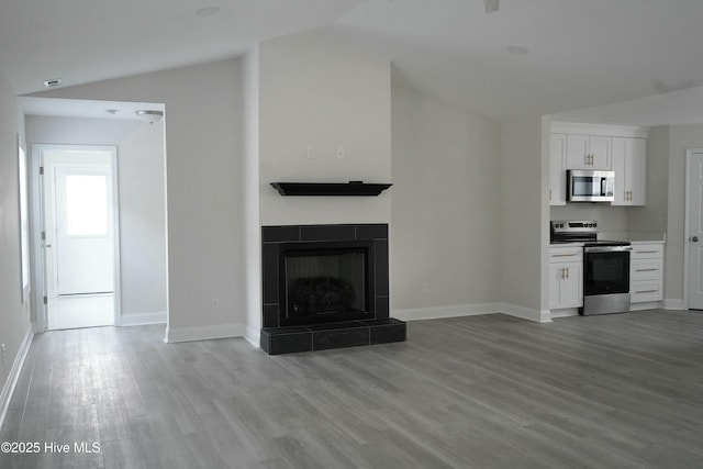 unfurnished living room featuring vaulted ceiling, light hardwood / wood-style floors, and a fireplace