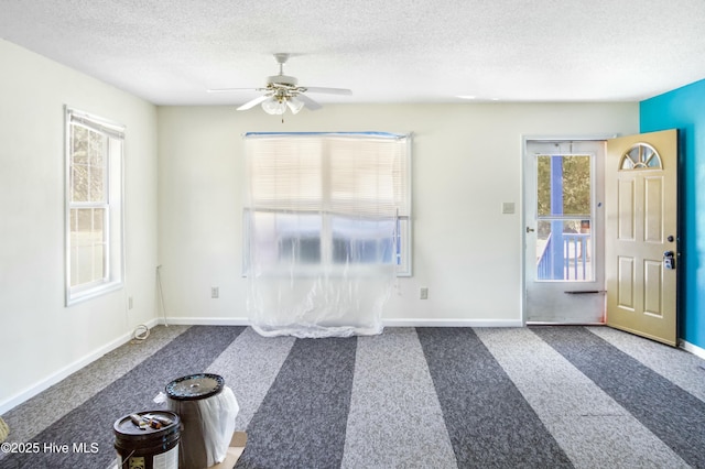 carpeted entrance foyer with ceiling fan and a textured ceiling