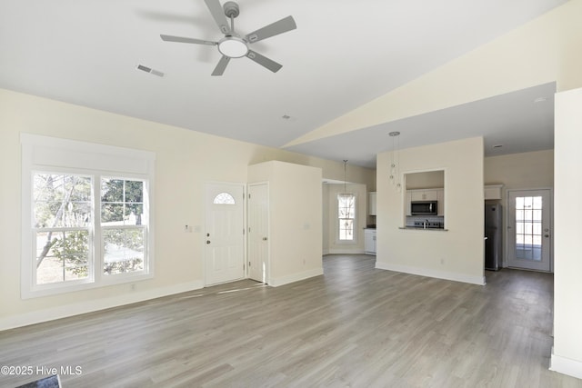 unfurnished living room with light hardwood / wood-style flooring, a wealth of natural light, ceiling fan, and vaulted ceiling