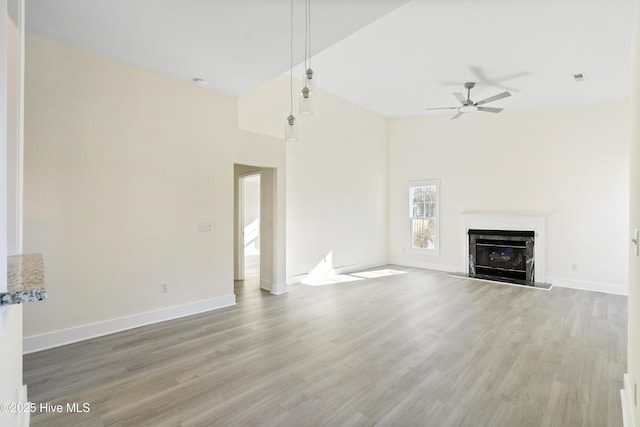 unfurnished living room featuring hardwood / wood-style flooring, a fireplace, ceiling fan, and a towering ceiling