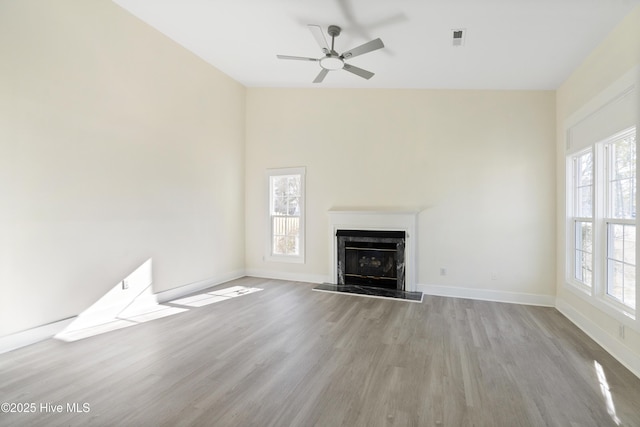 unfurnished living room featuring ceiling fan, a high end fireplace, and light wood-type flooring