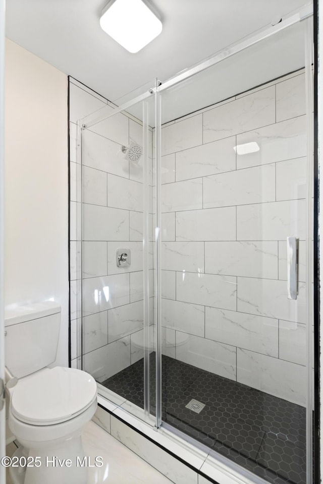 bathroom featuring tile patterned flooring, an enclosed shower, and toilet