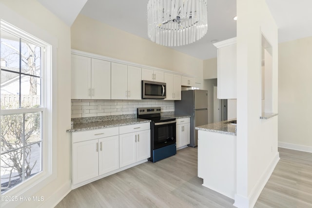 kitchen featuring light hardwood / wood-style flooring, stainless steel appliances, tasteful backsplash, light stone counters, and white cabinets