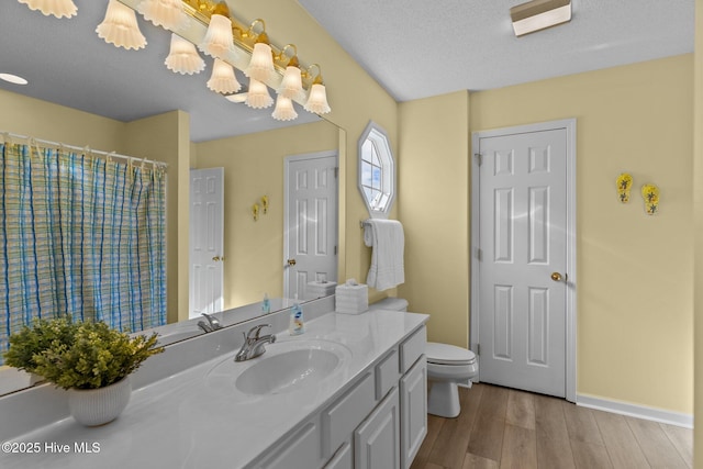 bathroom with a textured ceiling, hardwood / wood-style flooring, toilet, and vanity