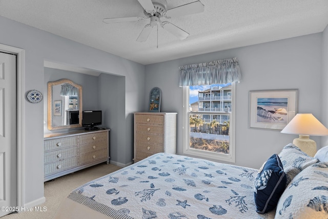 bedroom with light colored carpet, a textured ceiling, and ceiling fan