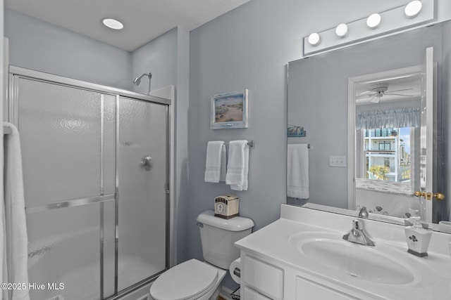 bathroom featuring toilet, a textured ceiling, walk in shower, vanity, and ceiling fan