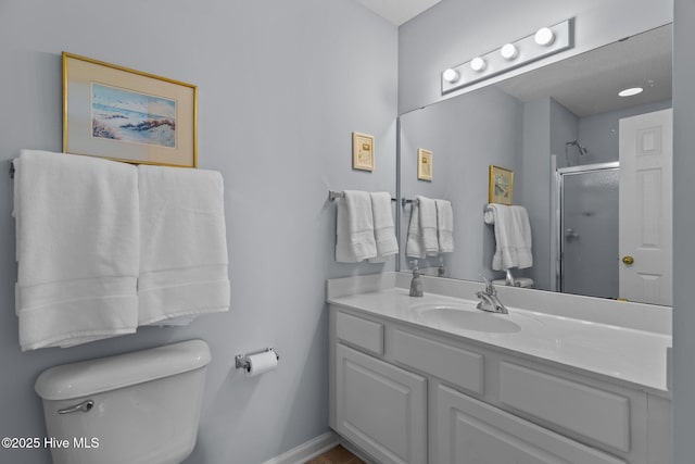 bathroom featuring a shower with door, toilet, and vanity