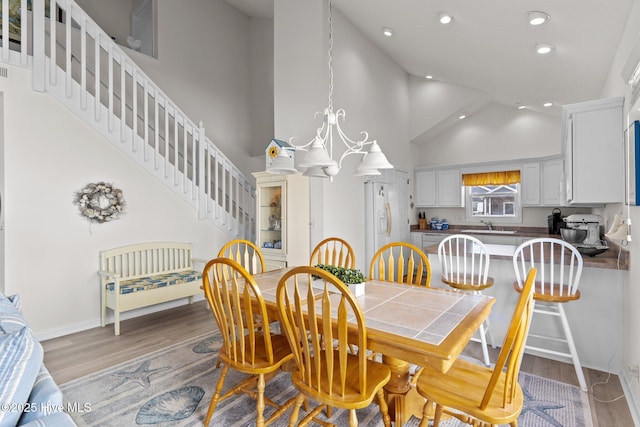 dining area featuring a notable chandelier, a high ceiling, light hardwood / wood-style floors, and sink