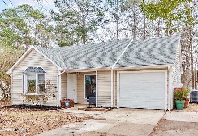 ranch-style house with a garage, concrete driveway, roof with shingles, and central AC