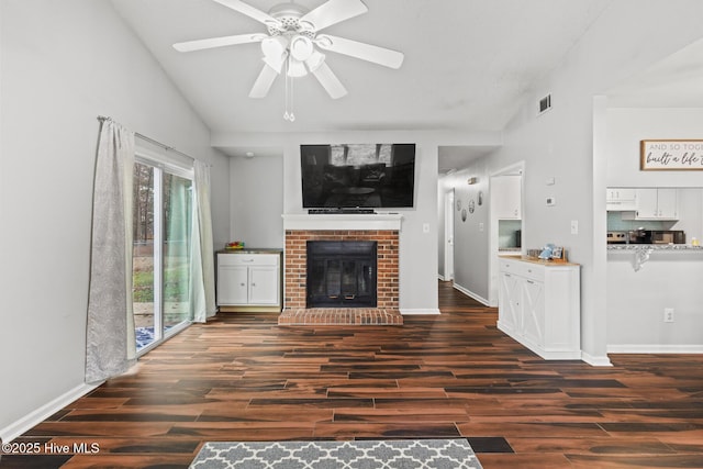 unfurnished living room featuring lofted ceiling, a brick fireplace, dark hardwood / wood-style floors, and ceiling fan