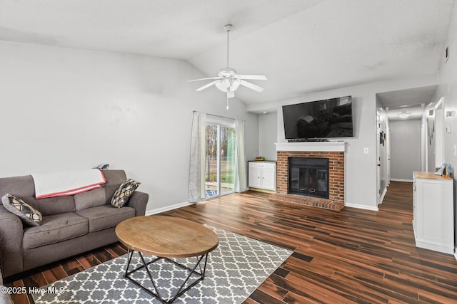 living room featuring a fireplace, dark wood-type flooring, ceiling fan, and vaulted ceiling