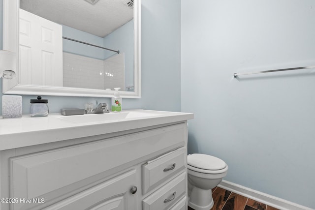 bathroom with a textured ceiling, toilet, wood finished floors, vanity, and baseboards