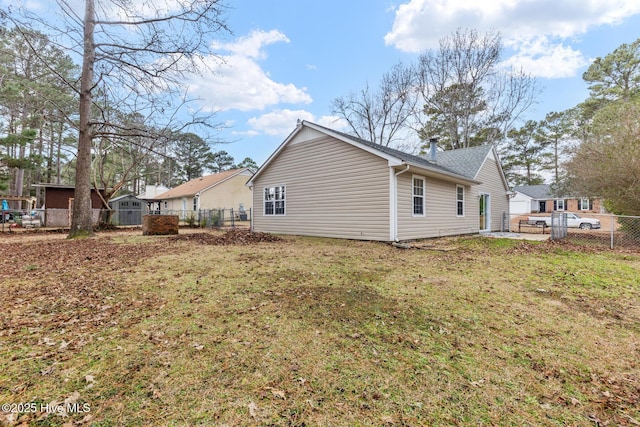 rear view of house featuring a fenced backyard, an outdoor structure, a lawn, and a shed