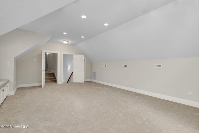 additional living space featuring vaulted ceiling and light colored carpet