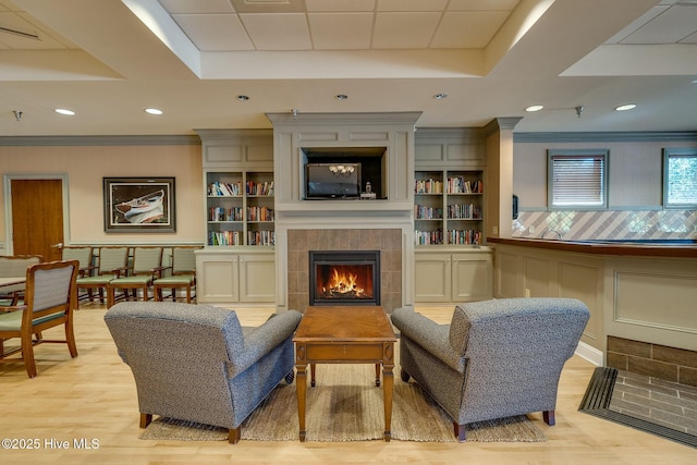 interior space featuring crown molding, a fireplace, light hardwood / wood-style floors, and built in features