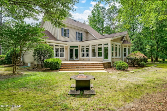 back of property featuring a sunroom, a yard, a fire pit, and french doors