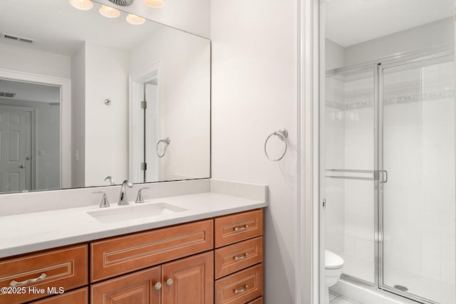 bathroom featuring vanity, toilet, and a shower with door