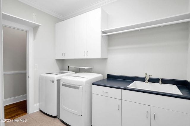 laundry area with crown molding, light tile patterned floors, sink, washing machine and dryer, and cabinets