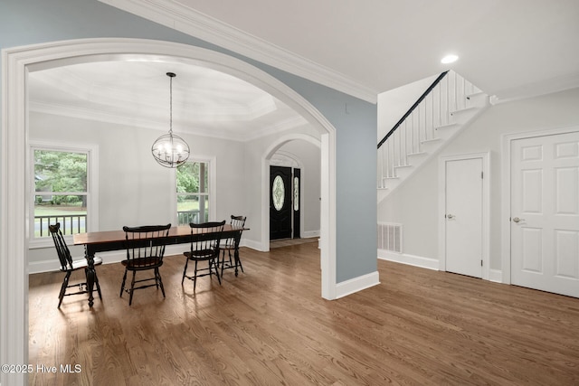 dining space with a chandelier, crown molding, and wood-type flooring