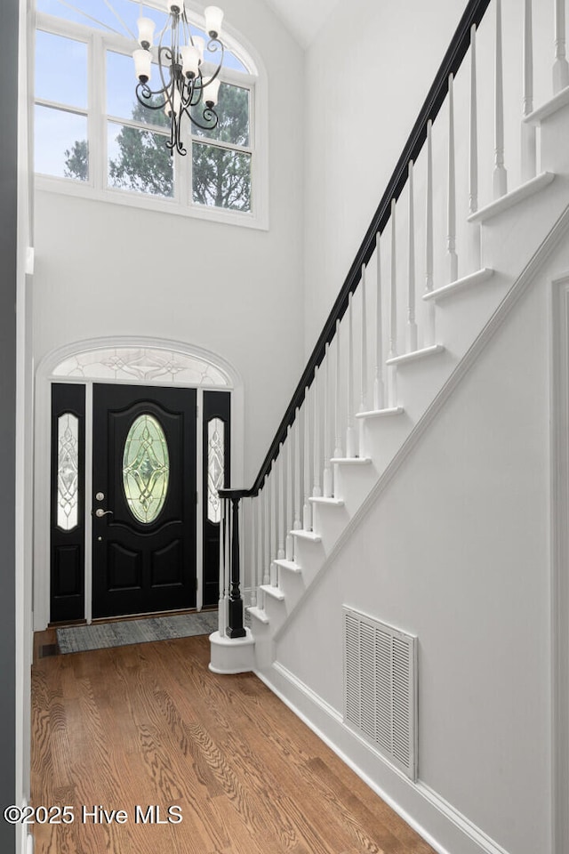 foyer featuring hardwood / wood-style flooring, a chandelier, and a high ceiling