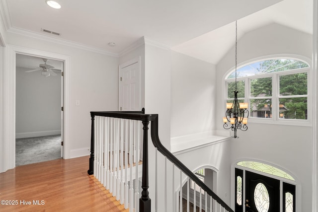 hallway with a notable chandelier, hardwood / wood-style flooring, vaulted ceiling, and plenty of natural light