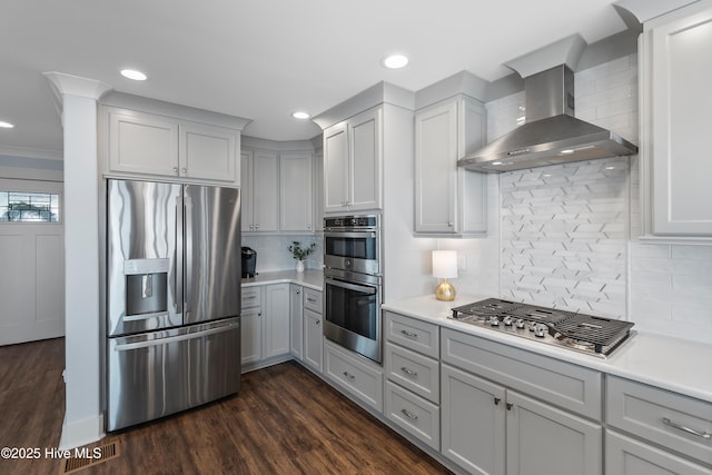 kitchen with gray cabinets, appliances with stainless steel finishes, backsplash, and wall chimney exhaust hood